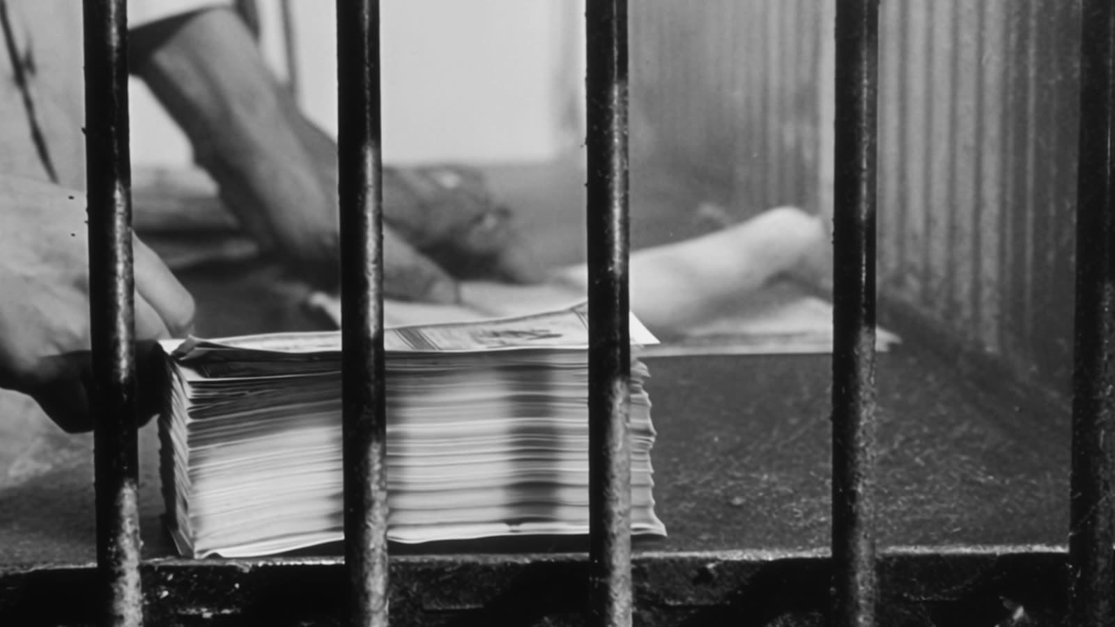 A stack of banknotes behind the bars of a pawnshop window.